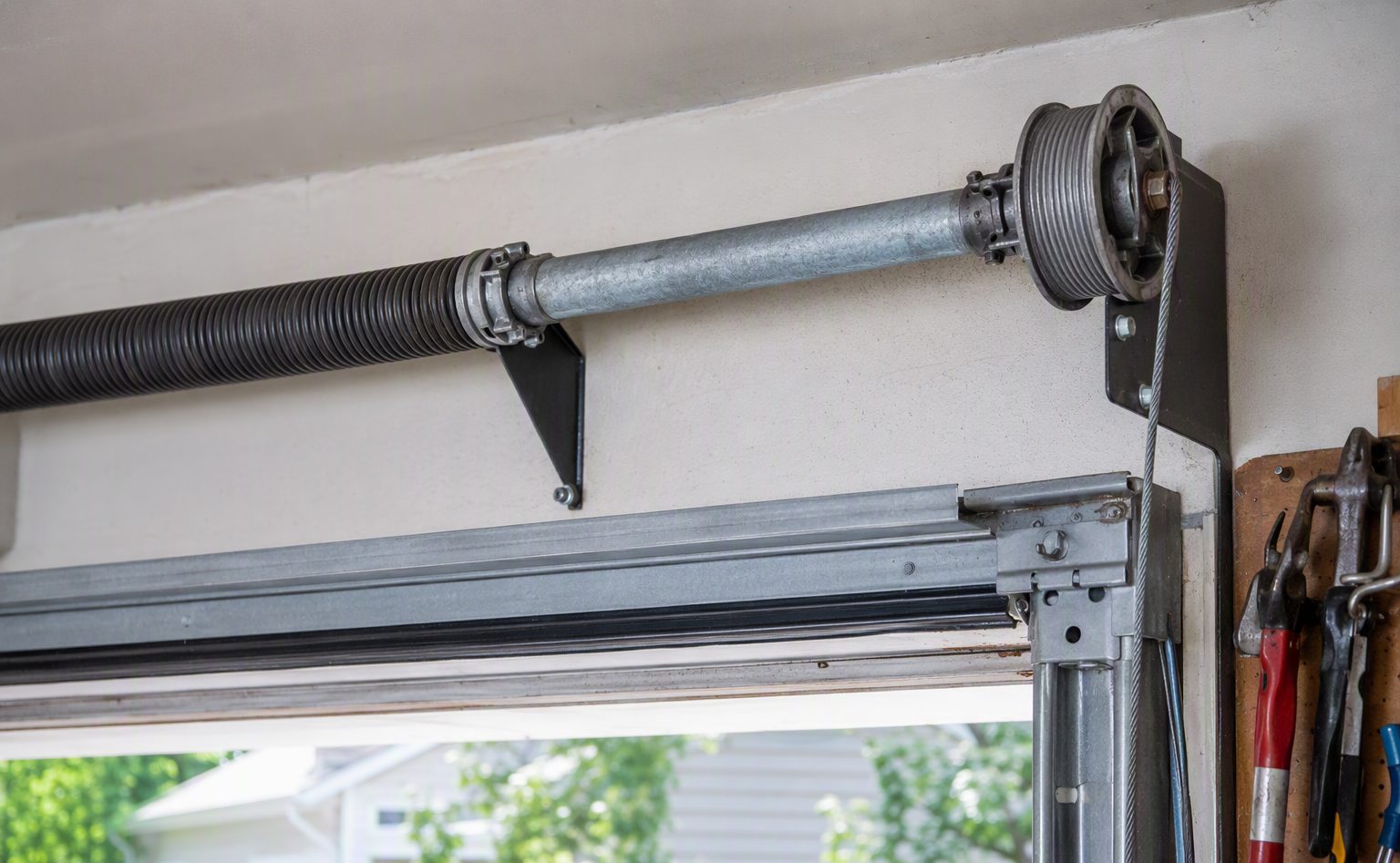 Garage door torsion spring and cable assembly above a sectional door